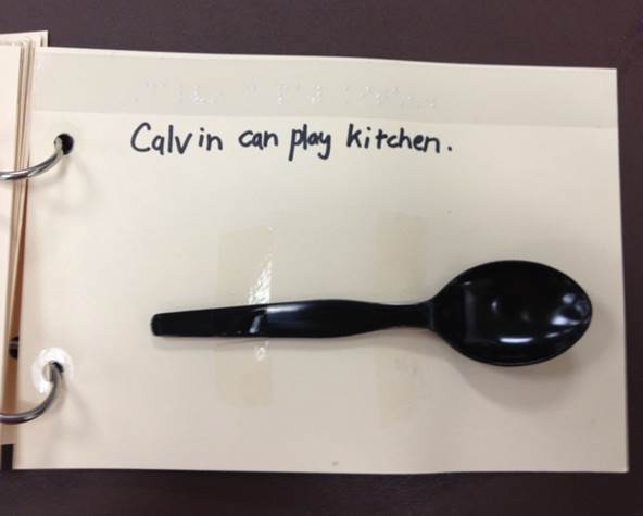 a page in a spiral notebook with a plastic spoon that says calvin can play kitchen
