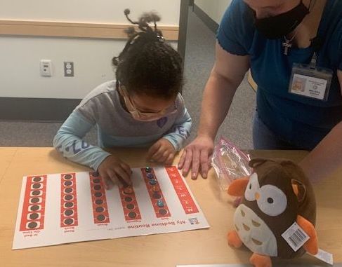 A young girl looks at her bedtime log with her teacher.