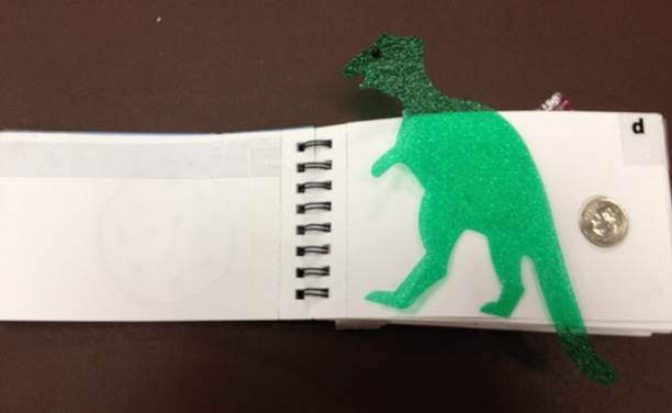 a spiral book with a green dinosaur to identify the letter d