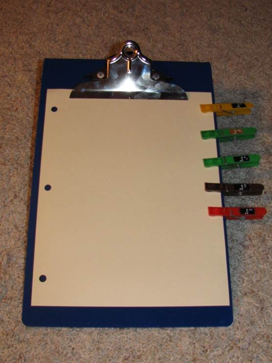 a clipboard with clothespins on one side and braille text on a piece of paper