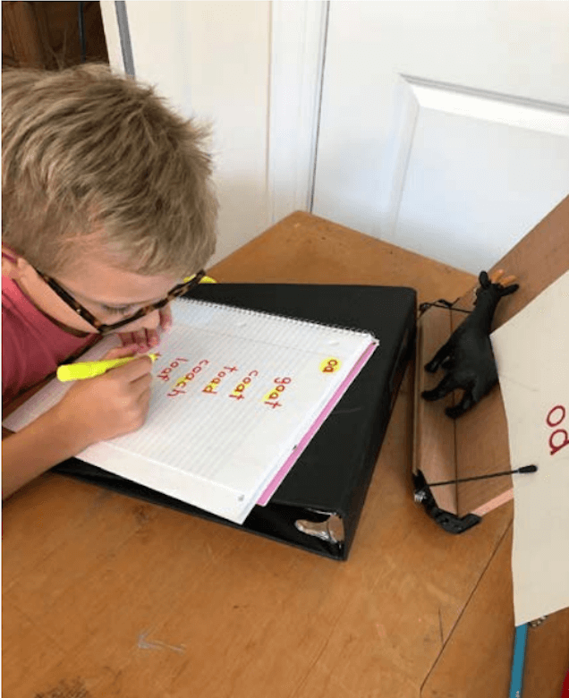 A boy highlights words written in red ink with a yellow highlighter