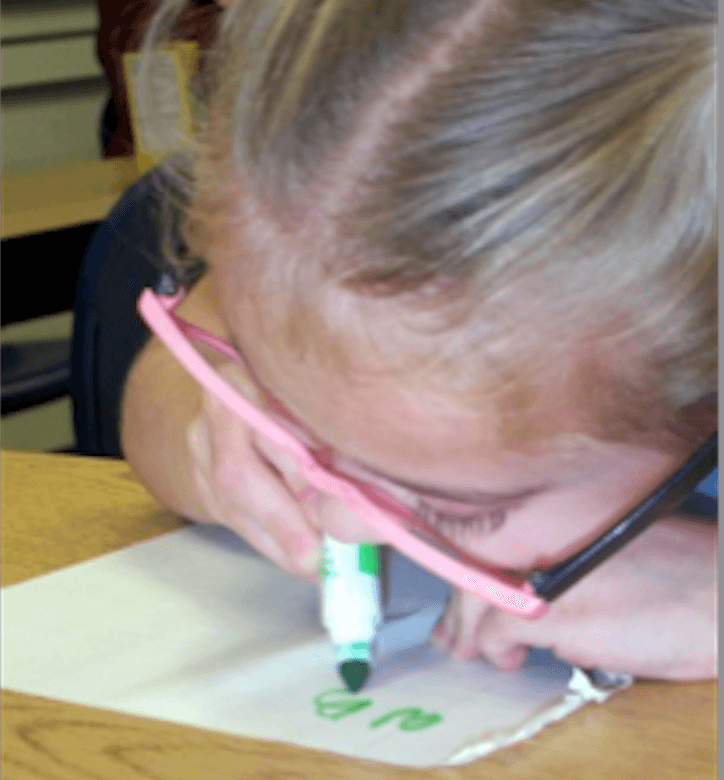 A girl writes with a green magic marker