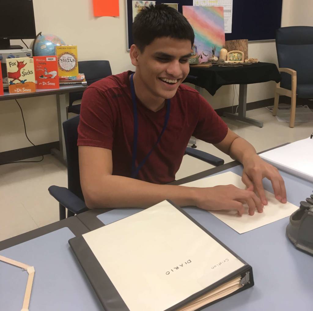 A teenage boy reading a page of braille.