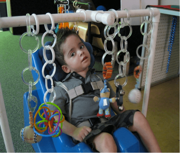 A young boy in an adapted seat gazes at a mobile.