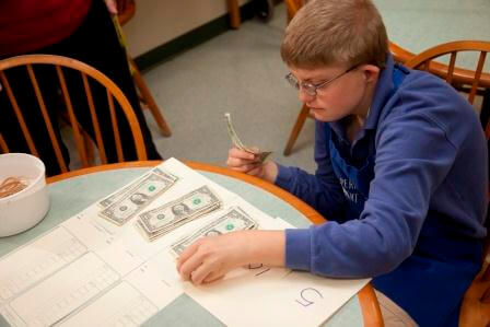 A boy with glasses counting dollar bills