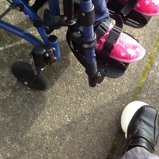 student's feet in wheel chair and another foot stepping on white balloon