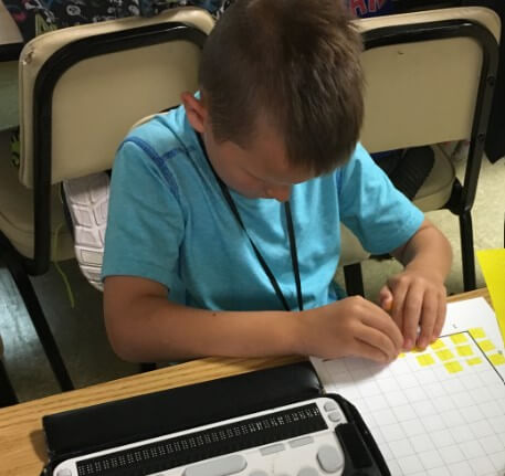 A boy examines a tactile bar graph.