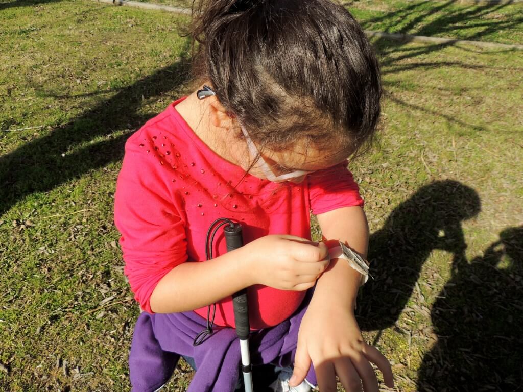  A young girl examines her tape bracelet. 