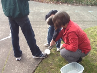 students looking at water balloon on ground