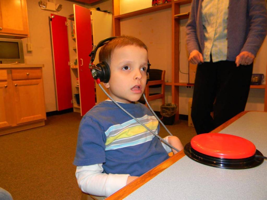 A young boy wearing headphones with a Big Mac switch on the table in front of him.