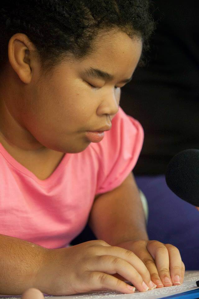 A young girl reads a page of braille text.