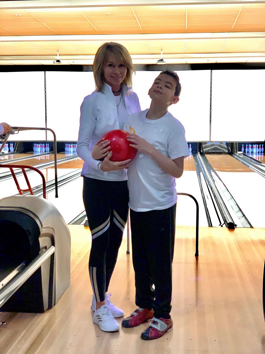 Aidan and Sherry hold a red bowling ball together during bowling activities at Special Olympics. A teacher and student hold a bowling ball