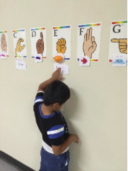 student using braille cards to read the alphabet chart