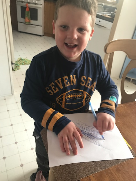 Click to enlarge the picture of Liam drawing on sandpaper. Liam drawing on a piece of paper that is over sandpaper