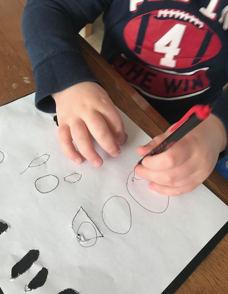 Click to enlarge the photo of Liam drawing shapes to punch out. Liam drawing shapes on the black board