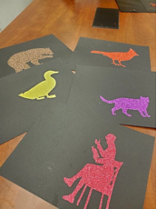 Colored silhouettes of animals on black pages
