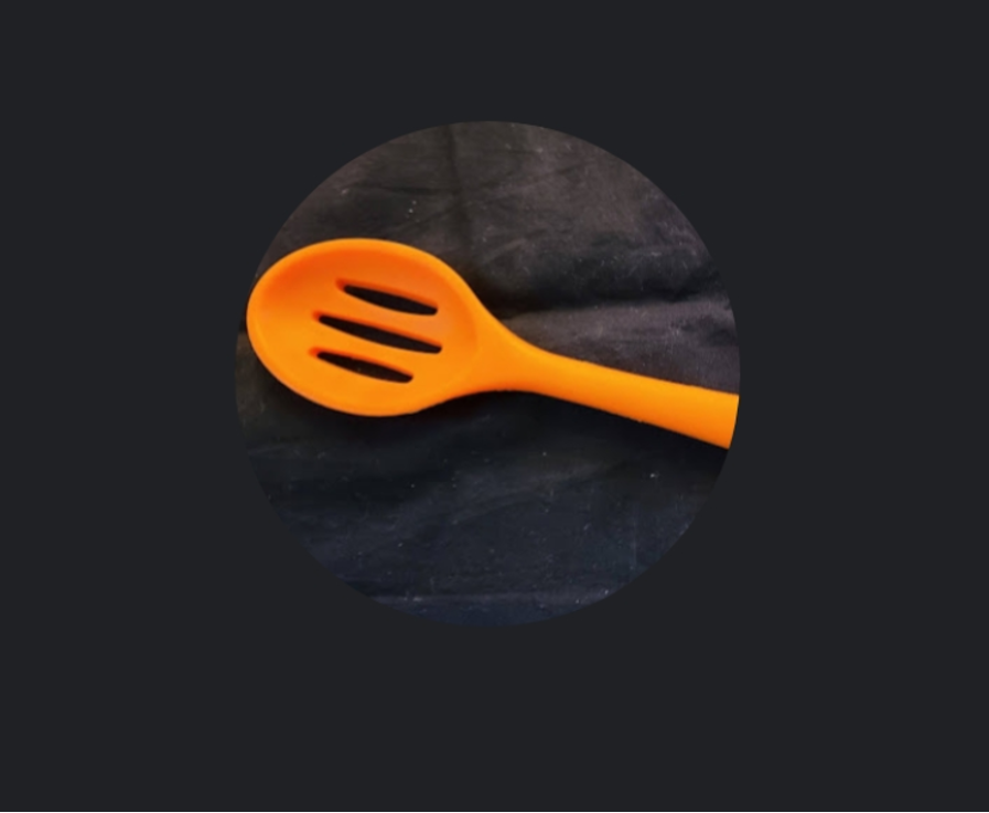 Orange slotted spoon on black background