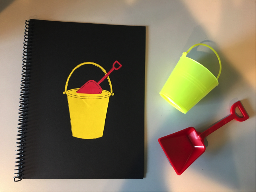 The red shovel is in the yellow bucket.