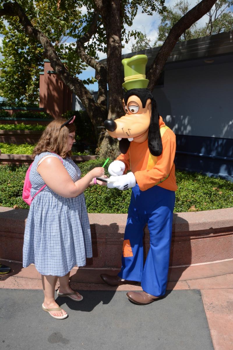  a person dressed as Goofy signs the autograph book