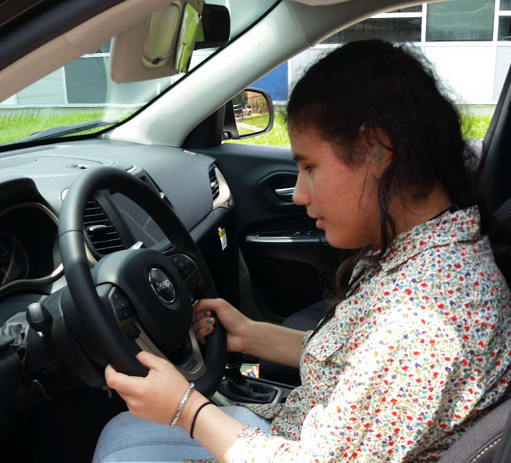 Heba, a young woman, sitting in a car with her hands on the steering wheel