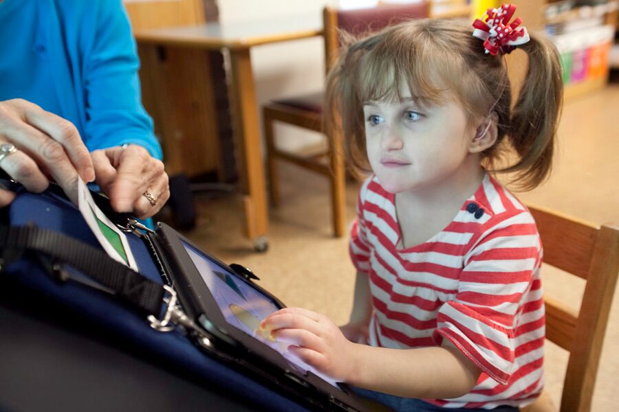 female student in striped shirt using iPad