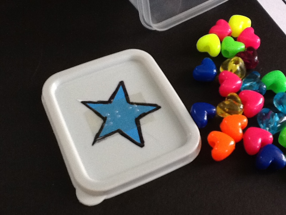 small beads and a star drawn on a tupperware cover