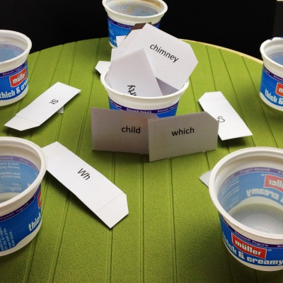 text and braille on pieces of paper and empty yogurt cups