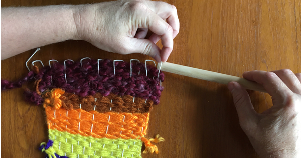 Inserting dowel through the loops at the top of the weaving