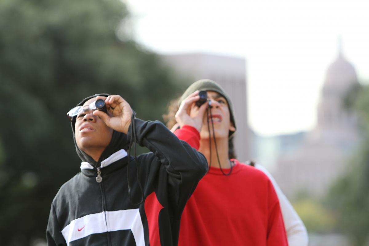 two boys use monoculars outside