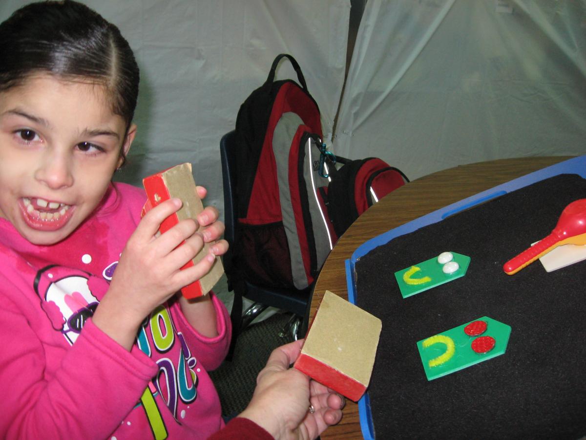 This happy student has a team of people that believe in her ability to make progress. Student using tactile items