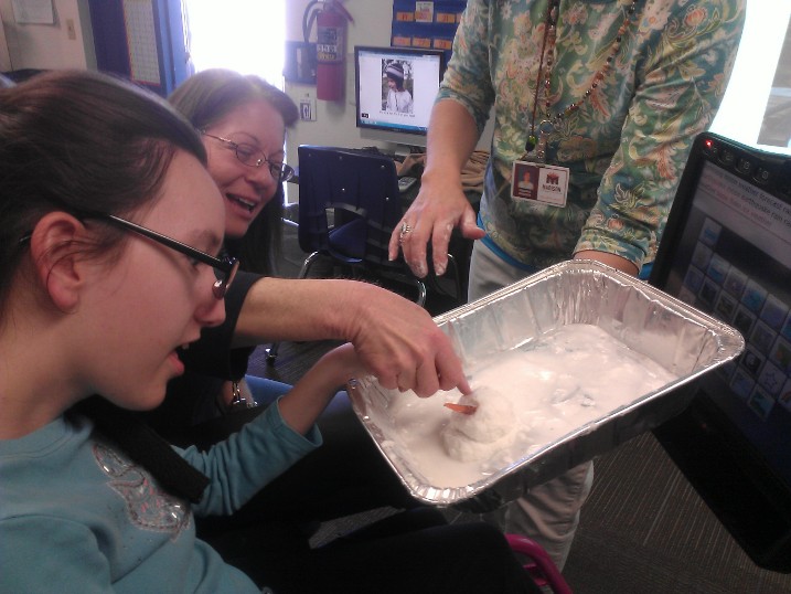 The TVI models techniques for a ParaPro during a group lesson. student feeling items in a cake pan
