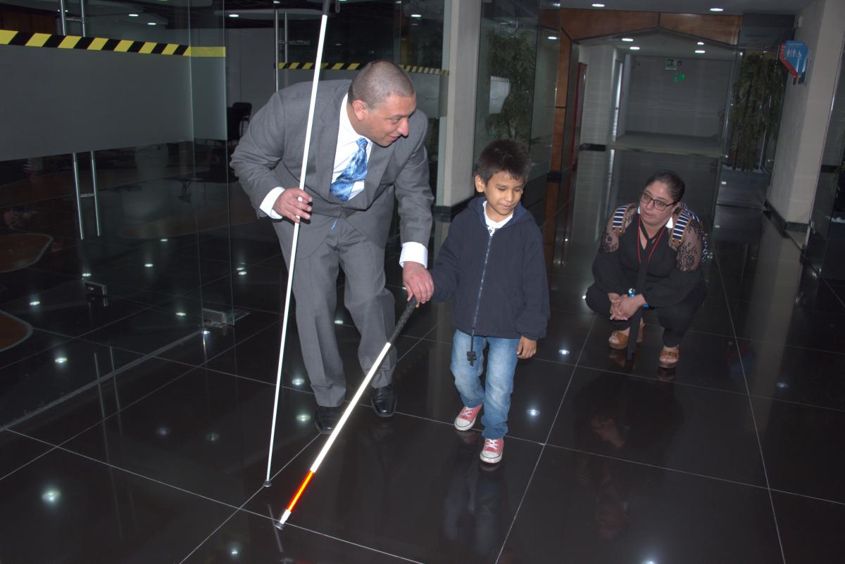 A student on an O&M lesson with the interpreter squatting nearby
