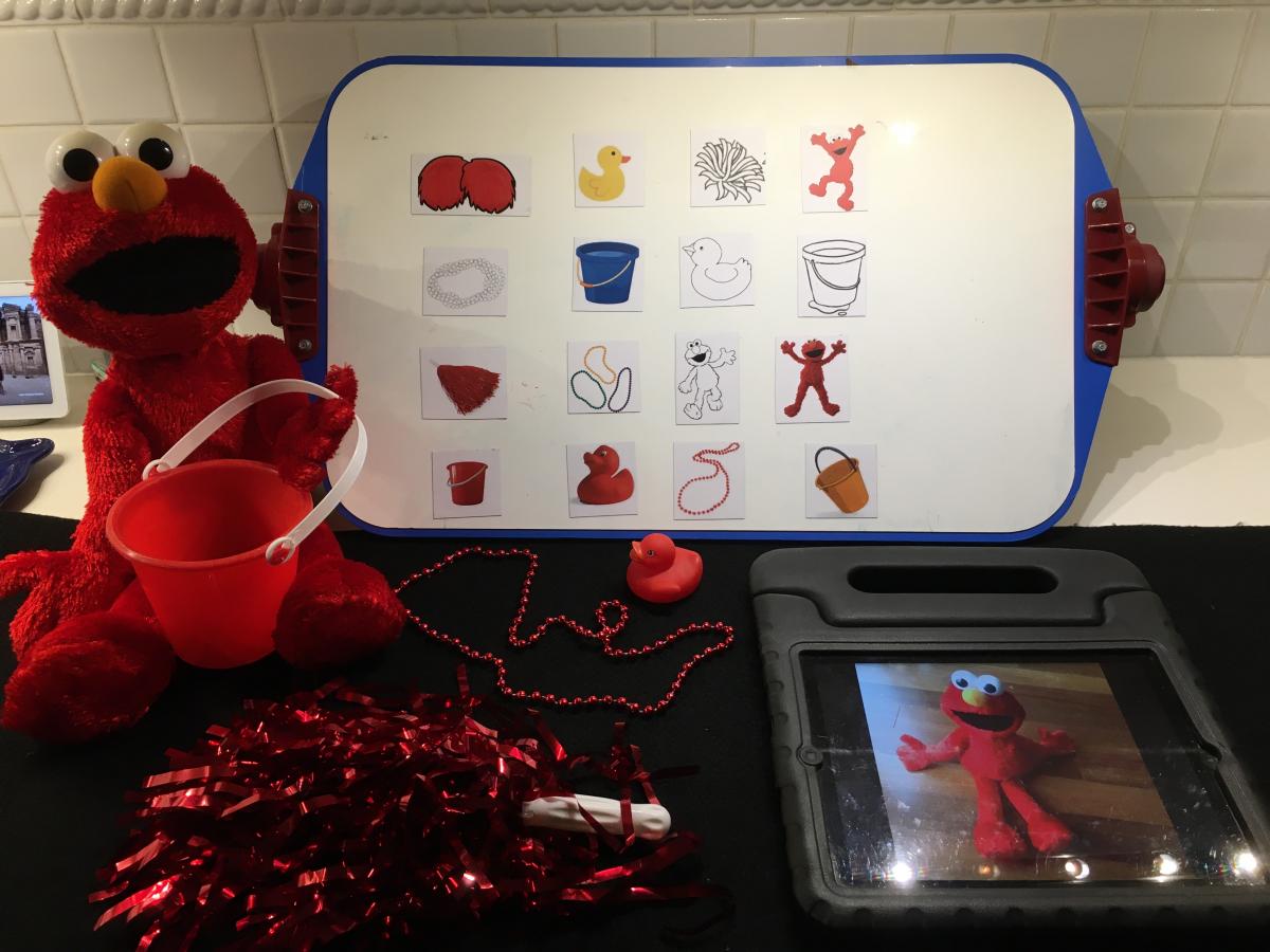 Elmo with red mylar pom pom, iPad and picture symbols on All-in-One Board
