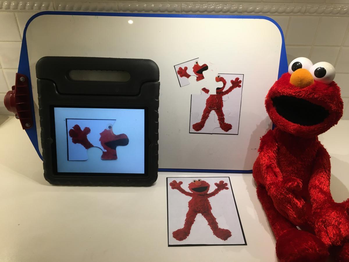Elmo puzzle with Elmo doll and image of puzzle on tablet