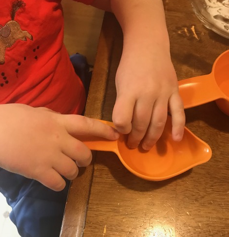 Liam reading the measurements on an orange measuring cup