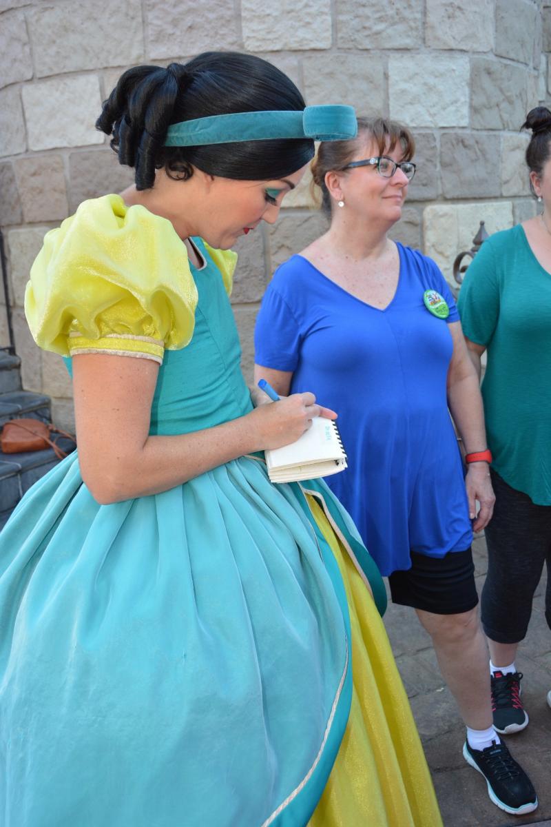 a woman dressed as a princess signing the autograph book