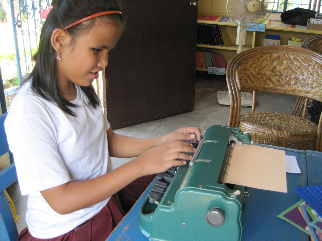 A girl writing on a Perkins braillewriter