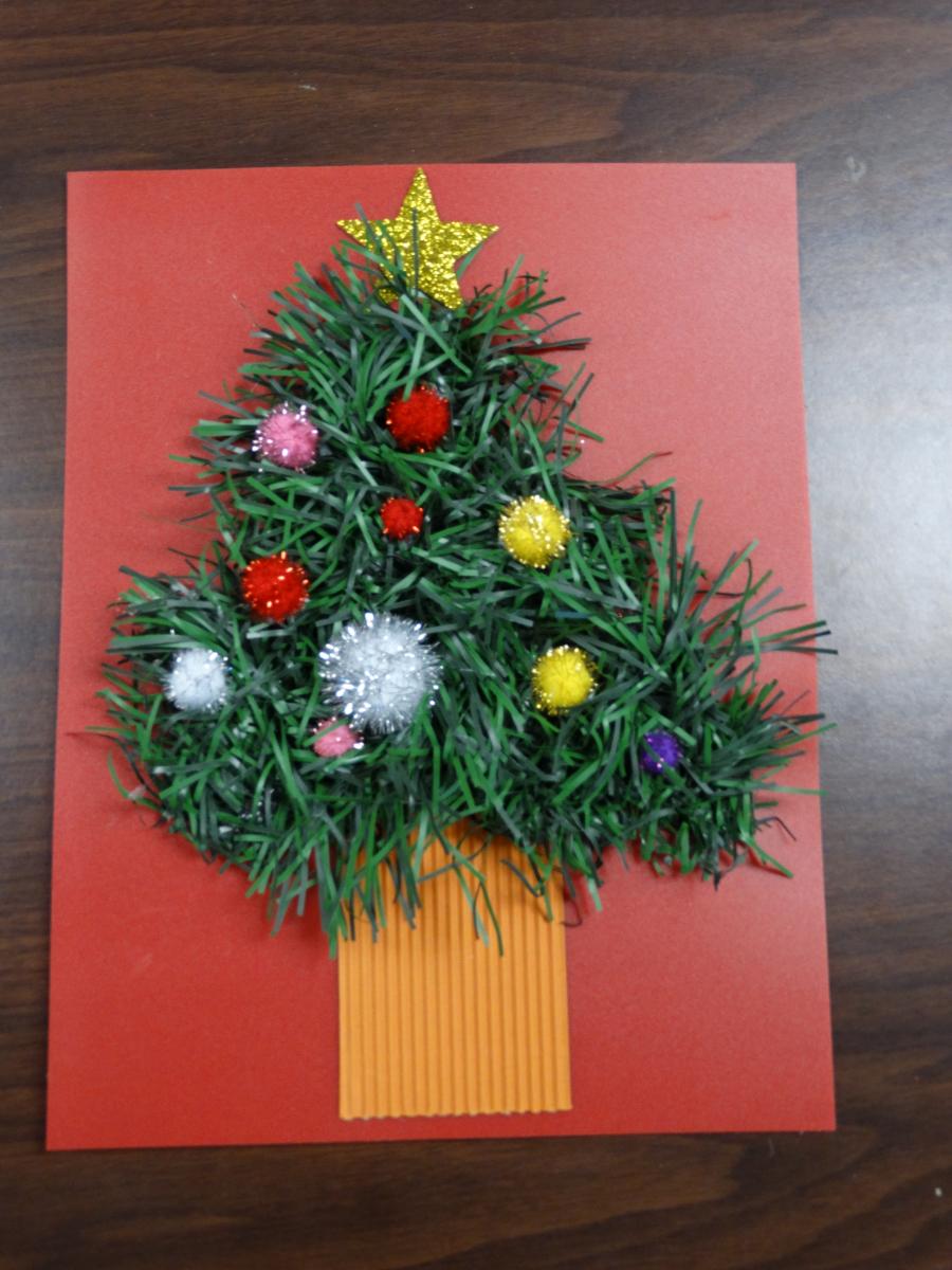 garland shaped into a tree on a red piece of paper with pom poms