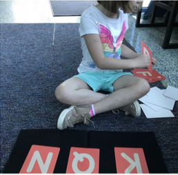 child with ABC flashcards sitting on floor 