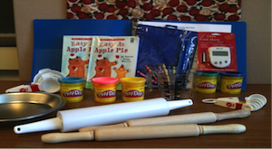 Kit with rolling pins, Play Doh, pie pans, and kitchen timer.