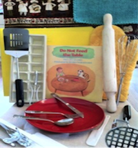 Kit includes oven mitts, placemat, can opener, spatulas, pancake flipper, plate and silverware