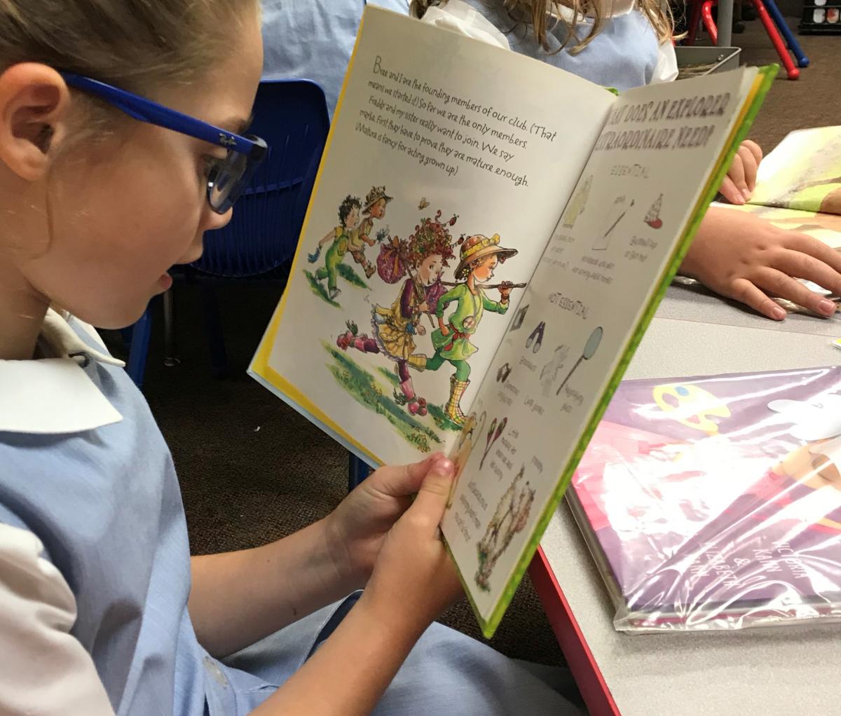 Child reading a picture book at class table