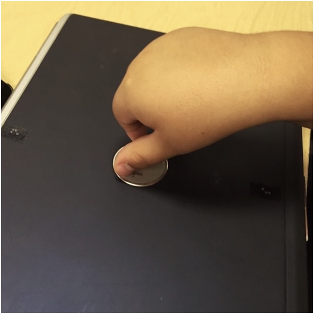 student's hand is showing rotor gesture on top on closed laptop