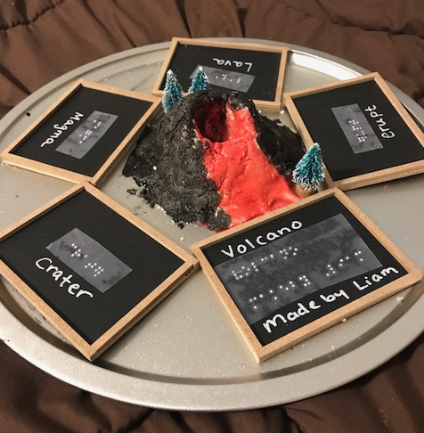 volcano vocabulary cards with text and braille surrounding the volcano model