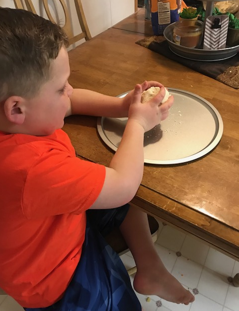Liam is making the playdough into a volcano shape. Liam moulding the playdough