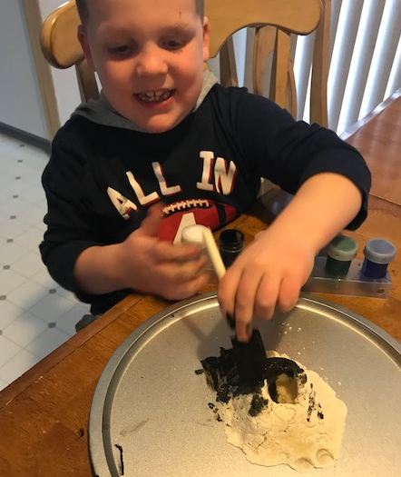 Liam painting the volcano with black paint and a sponge brush