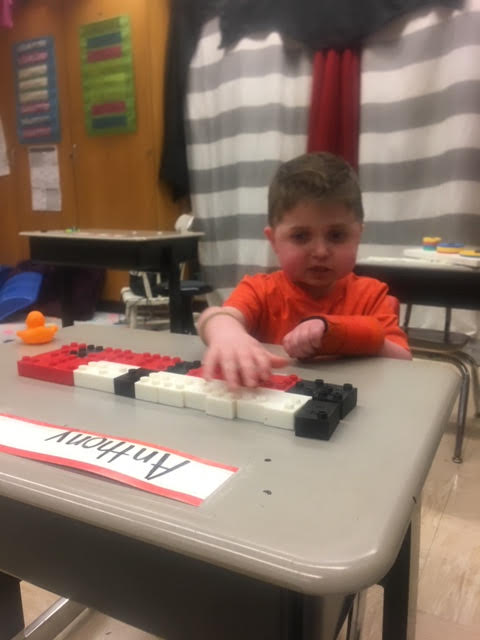 A boy using Duplo braille blocks at his desk