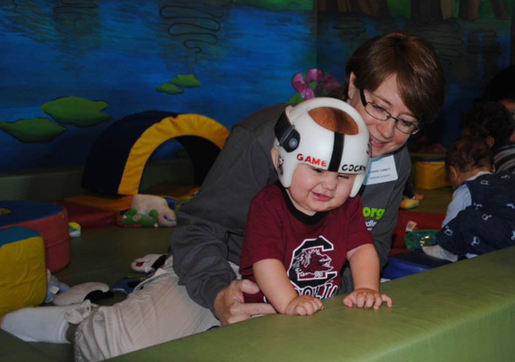 A boy reaches up on a bolster.