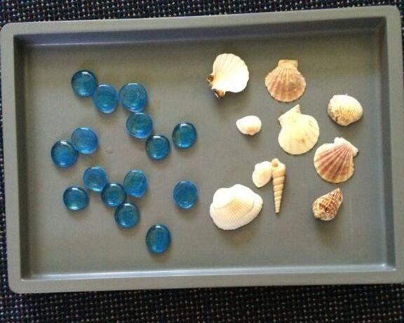 Click to enlarge sensory tray with summer theme Sensory Tray with glass beads and seashells.