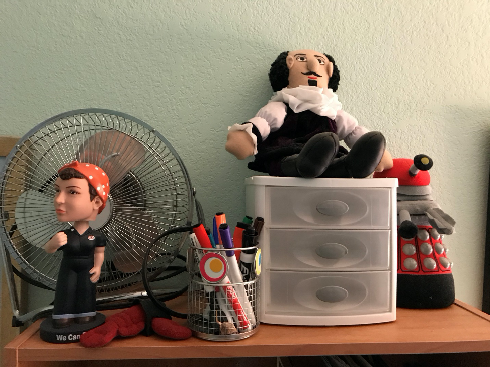 Fan, dolls, plastic drawers on desk